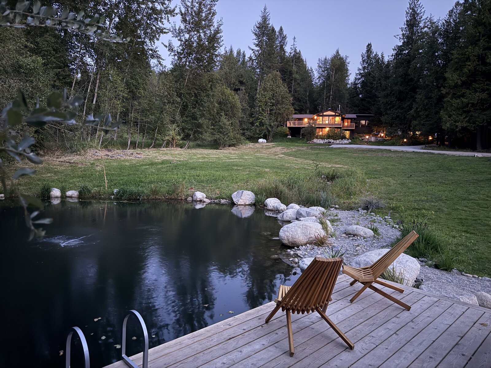 The cabin lit up at dusk from the pond dock